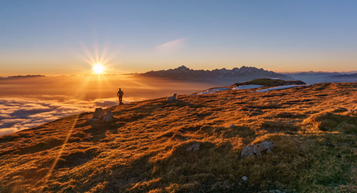 Hiker and a dog at the top of the mountain at Sunset. Beautiful